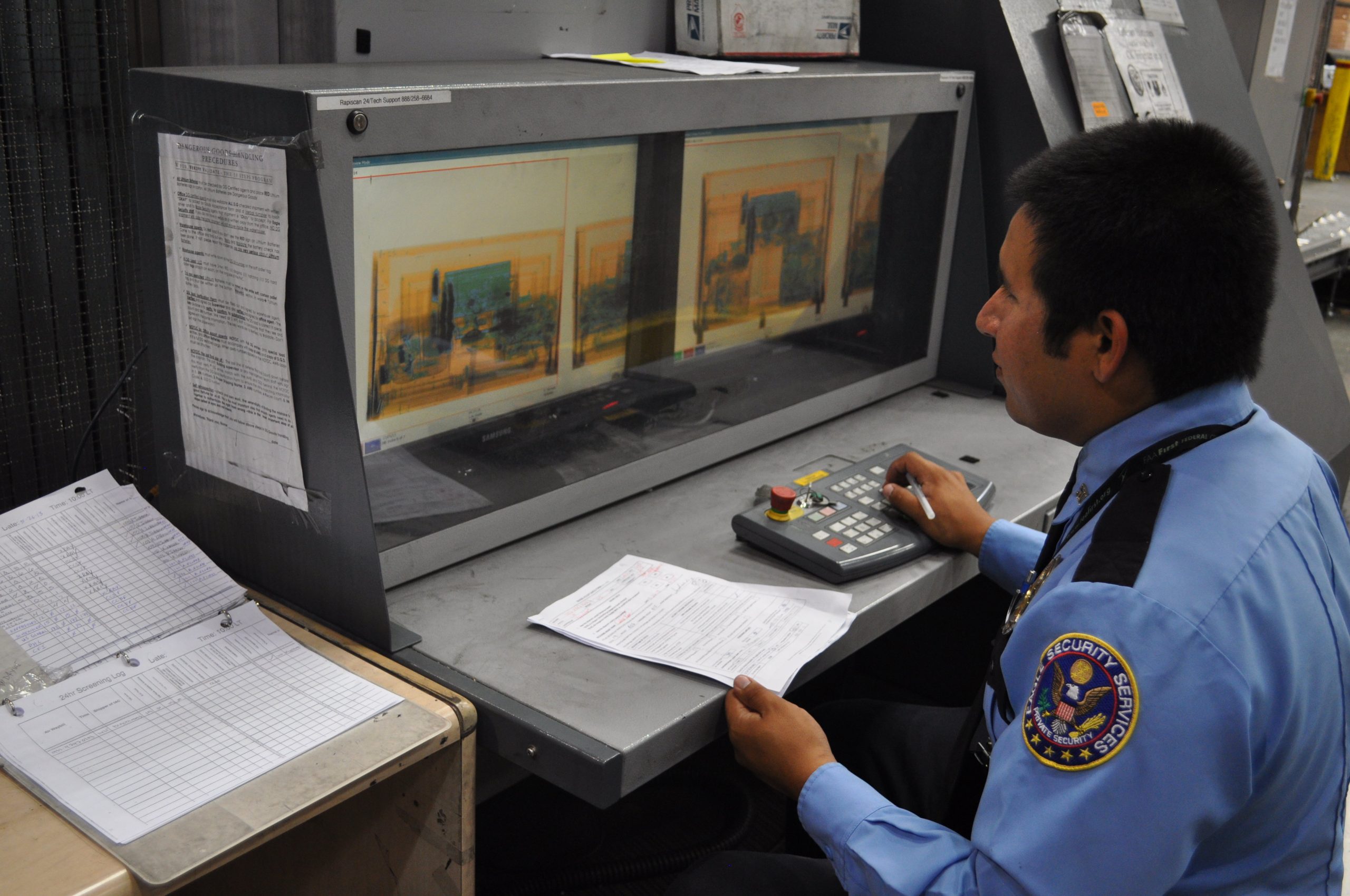Security officer examining cargo X-ray images on a monitor.