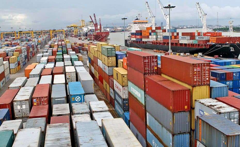 Rows of shipping containers beside a container ship at a terminal.