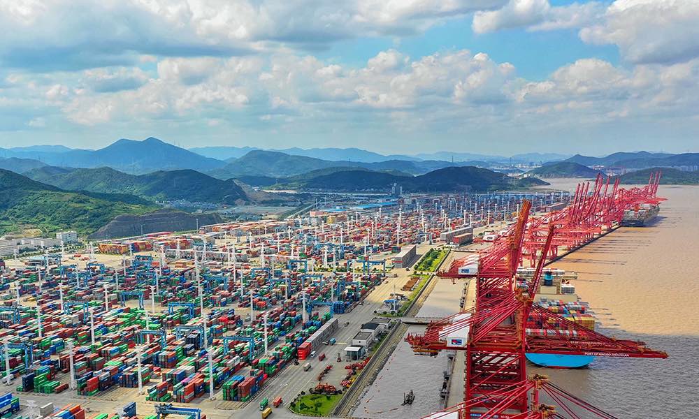 Container terminal with cranes and stacked shipping containers.