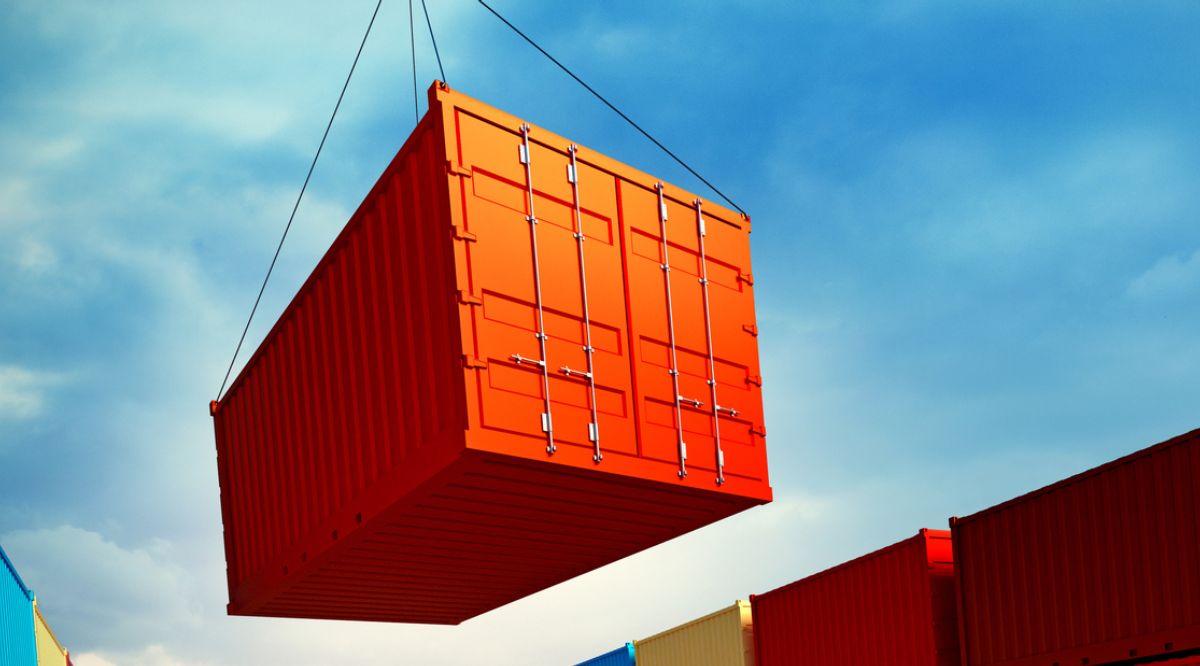 Orange shipping container being lifted by a crane.