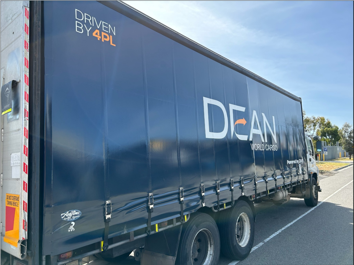 DEAN World Cargo delivery truck travelling on a road.