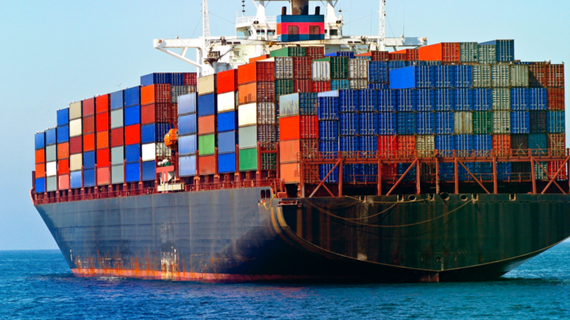 Container ship carrying stacked shipping containers at sea.