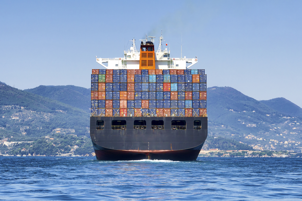 Container ship carrying stacked containers, viewed from the stern.